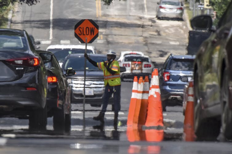 A worker in a reflective vest holds a 