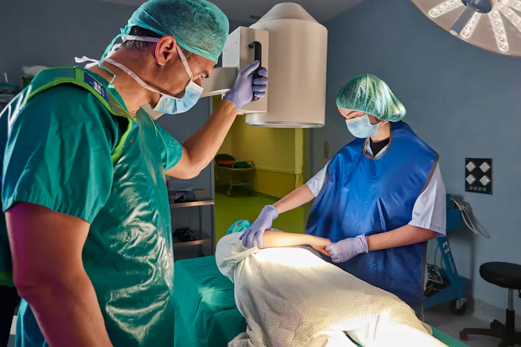A surgeon and nurse inside the operating room using an X-ray machine