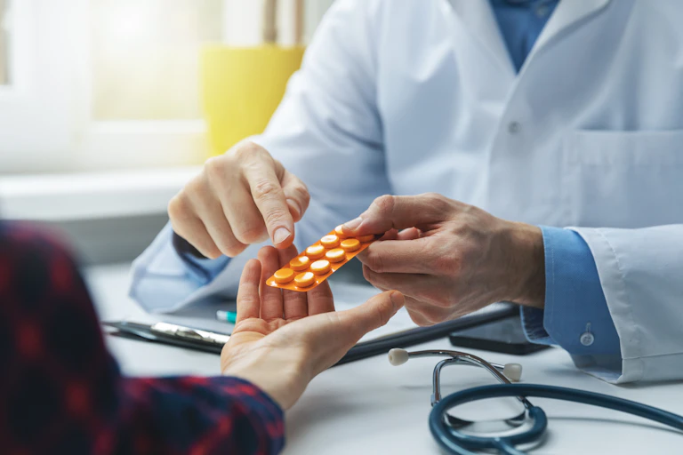 Provider handing a patient an orange blister pack.