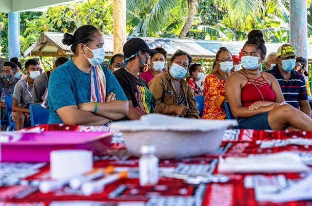 Une groupe de Tahitiens masqués attend d'être vacciné dans un centre de Tahiti.