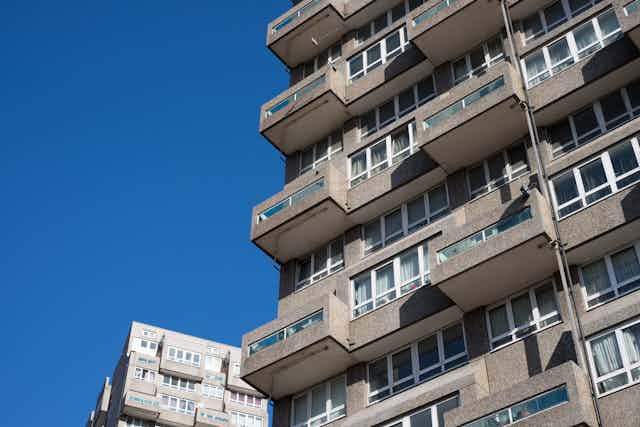 Grey balconies of a council high rise block set against a blue sky