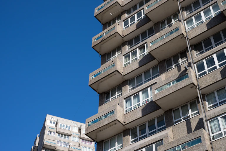 Grey balconies of a council high rise block set against a blue sky