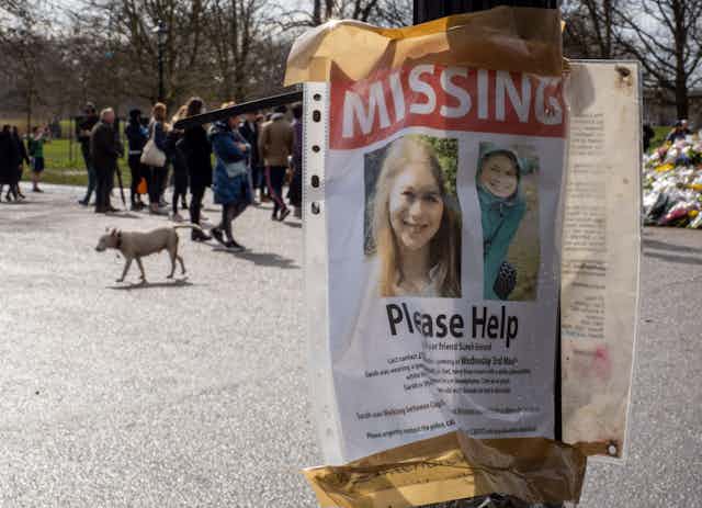 A missing poster for Sarah Everard seen on a post in front of the memorial for her
