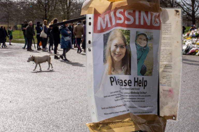 A missing poster for Sarah Everard seen on a post in front of the memorial for her