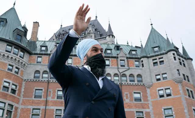 Jagmeet Singh waves in front of a building in Quebec City