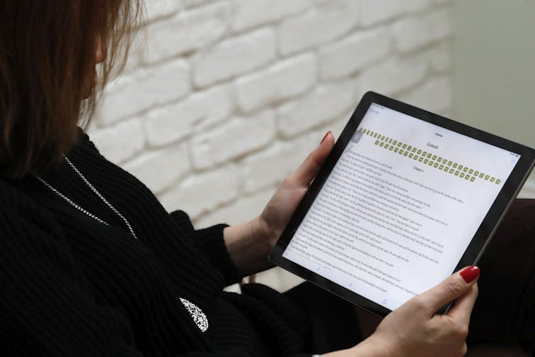 Woman reading the bible on a digital tablet Ipad. France.