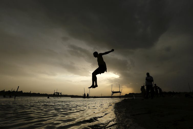 Boy mid-air above a river at sunset