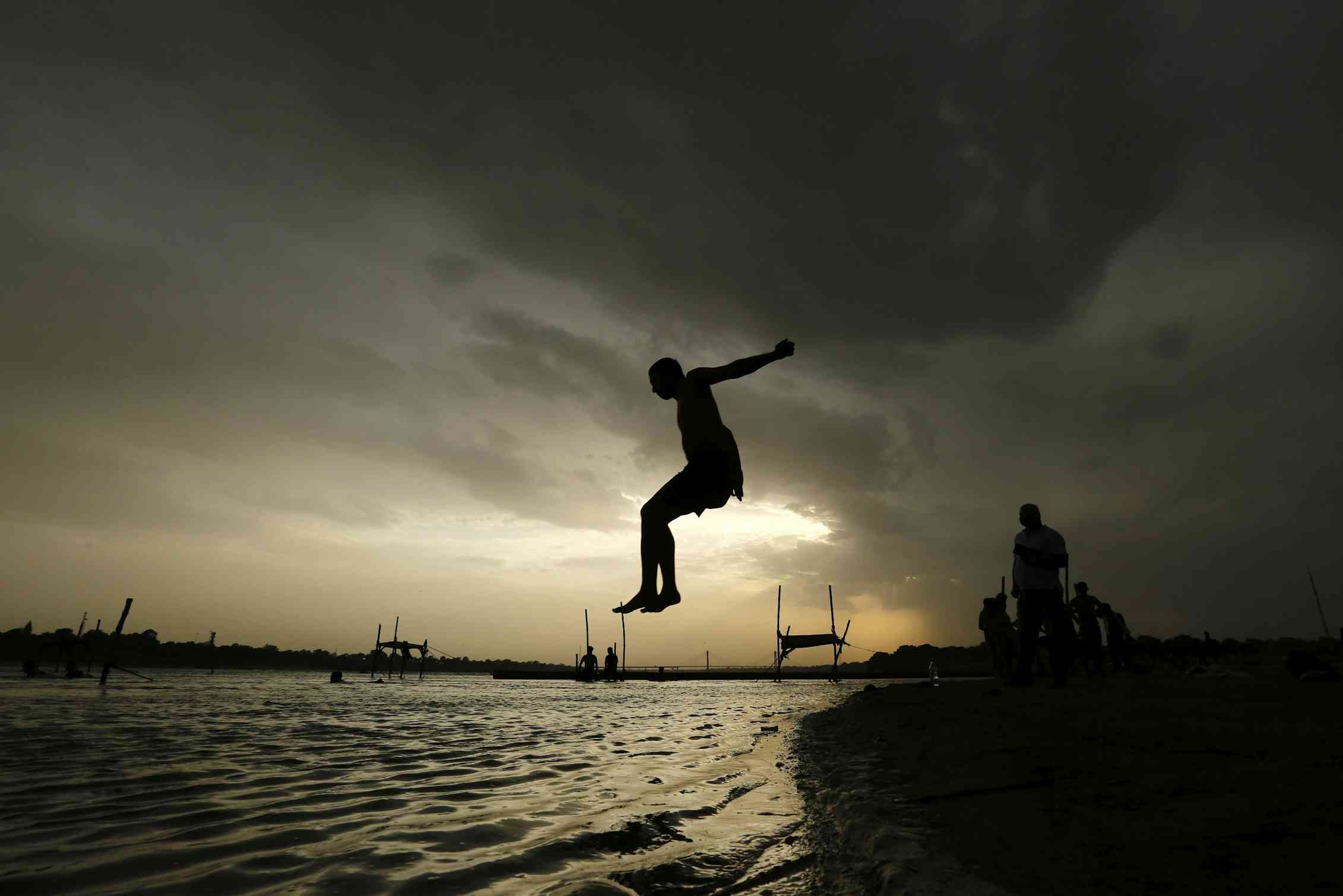 Boy mid-air above a river at sunset