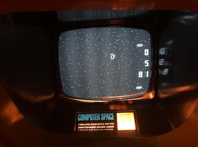 a cathode ray tube screen recessed in a cabinet displaying a black field with star-like white dots