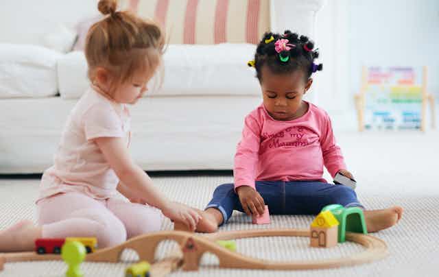 Two children play with blocks on the floor.