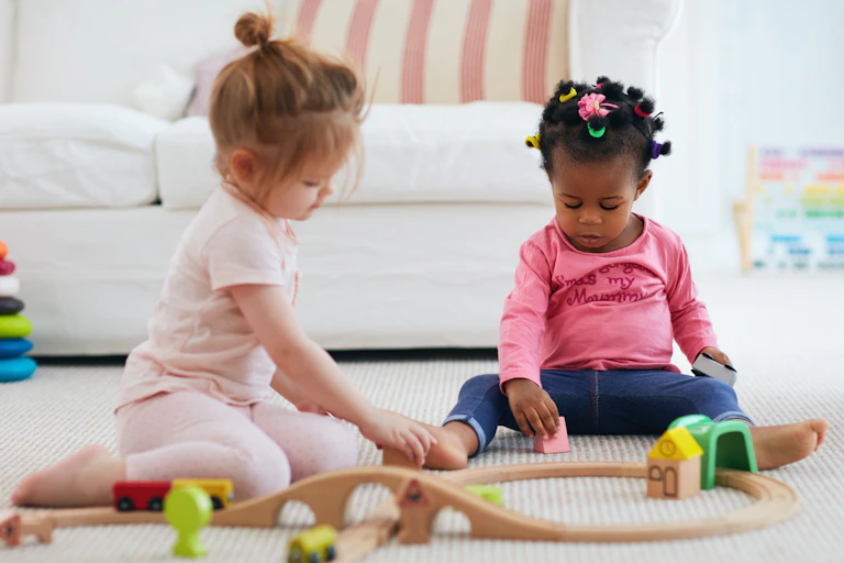 Two children play with blocks on the floor.