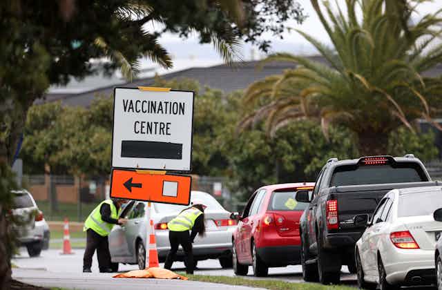 vaccination centre sign and line of cars