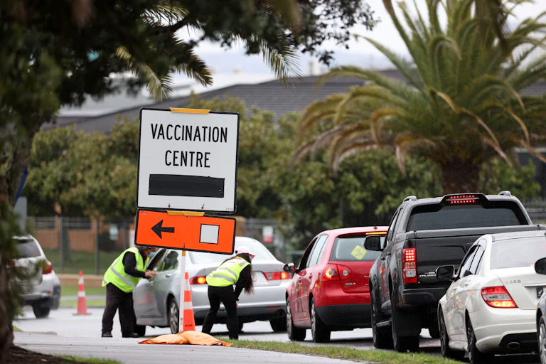 vaccination centre sign and line of cars