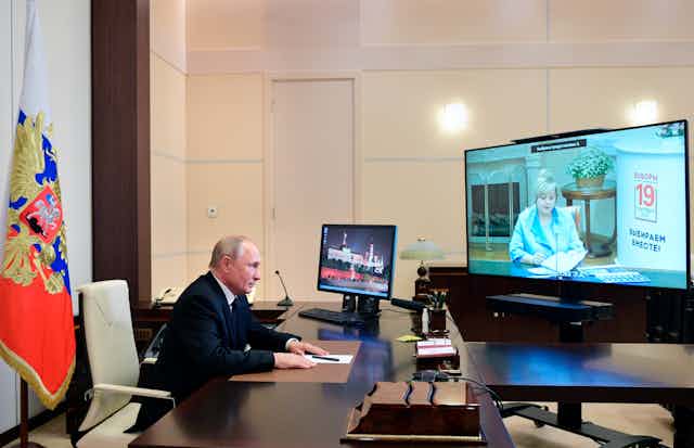 Vladimir Putin sits at desk, engaged in an online meeting