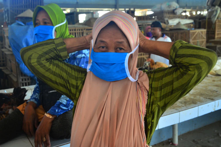 Seorang perempuan paruh baya memasang masker.