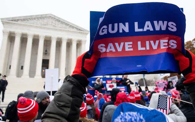A protester holds aloft a sign saying "gun laws save lives" at a rally in front of the Supreme Court.