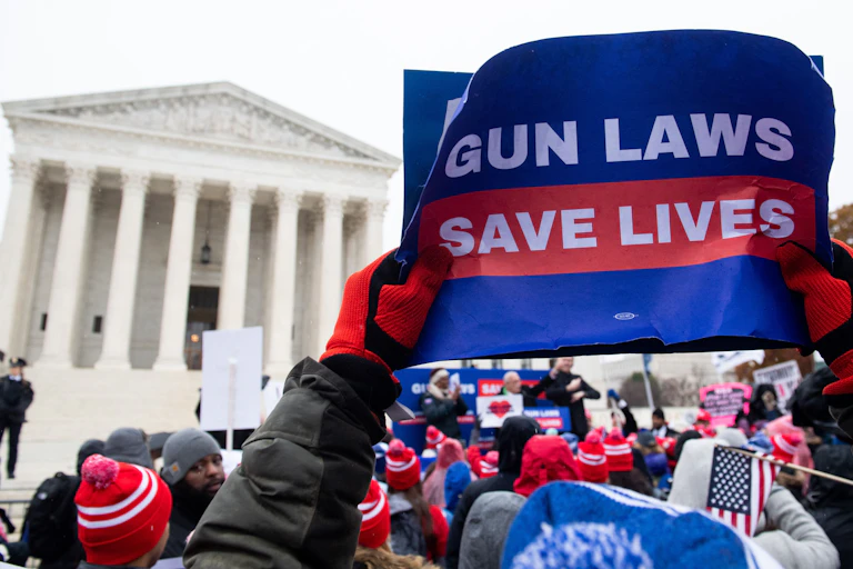 A protester holds aloft a sign saying "gun laws save lives" at a rally in front of the Supreme Court.