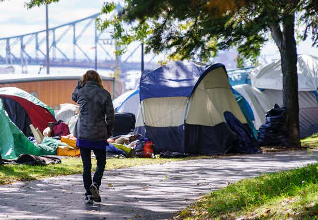 A woman walks past a row of tents set up by homeless people in Montréal.