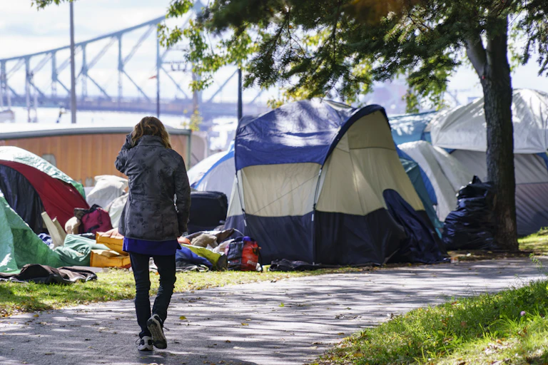 A woman walks past a row of tents set up by homeless people in Montréal.