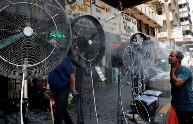 A man stands in front of floor fans on a street in Baghdad