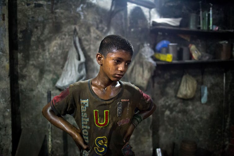 A boy in T-shirt with USA on it stands in a room sweating, his hands on his hips.