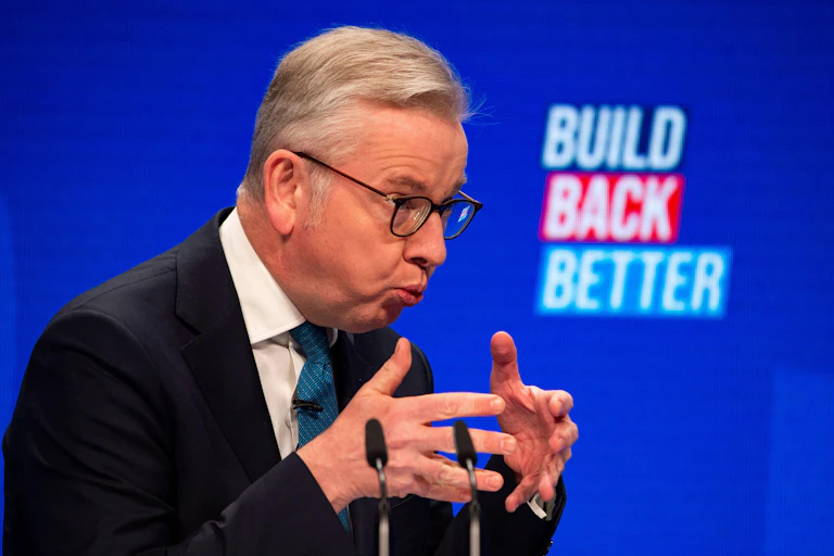 Michael Gove making a speech in front of a sign reading 'build back better'.