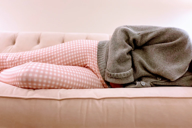 woman lying on a couch in pain