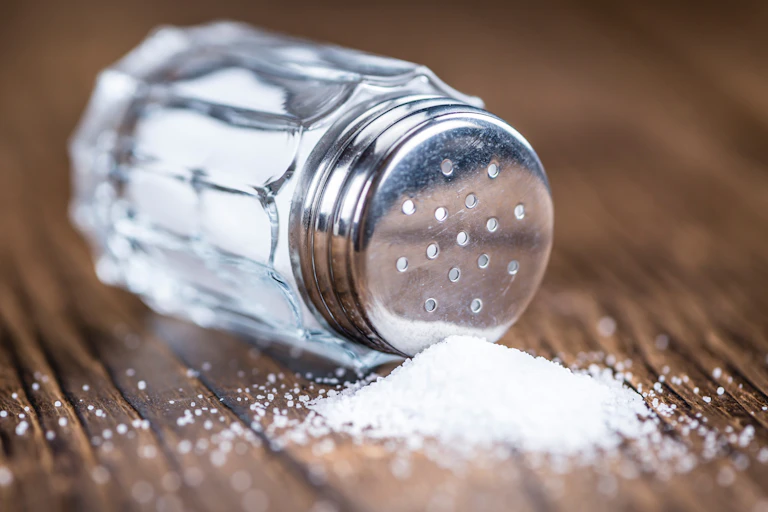Salt shaker knocked over on a wood table.