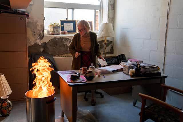 Woman burns documents in metal rubbish bin in office