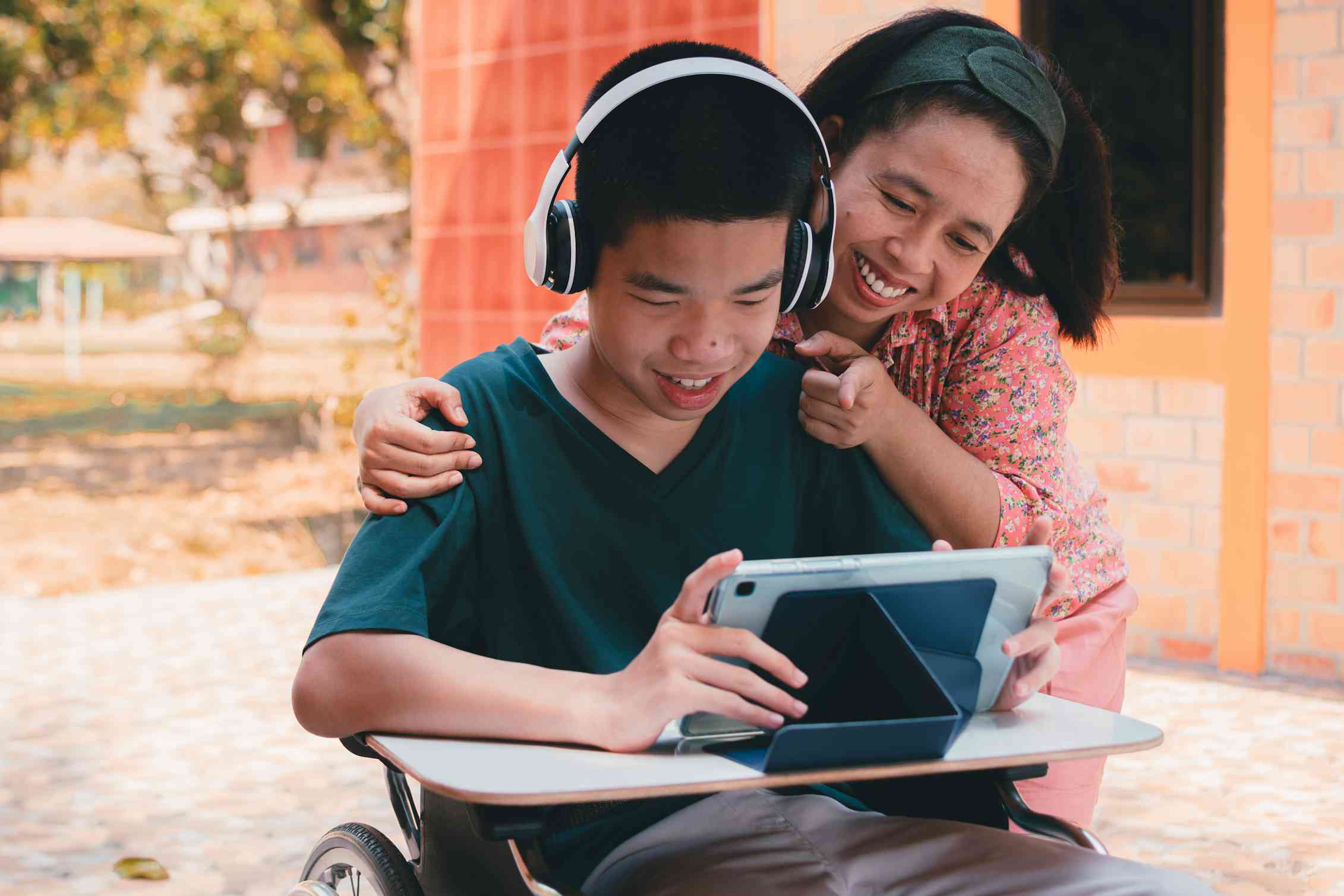 A student with disability on his Ipad, with Mum looking on behind him.