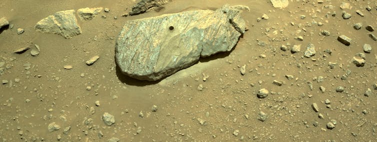 Una roccia sulla superficie bruno-rossastra con un foro circolare praticato nella parte superiore.