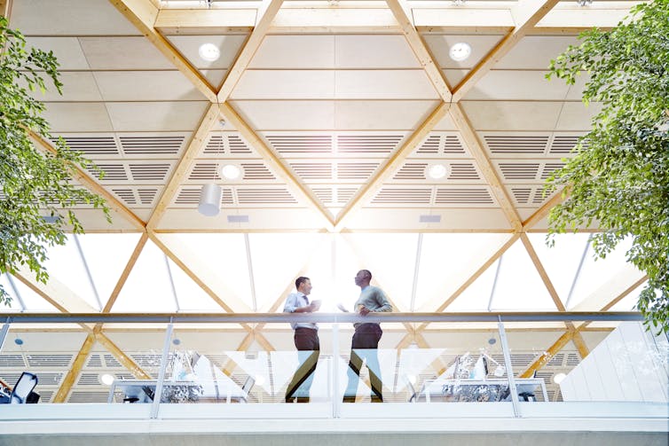 Two men chat in a high-end office environment.