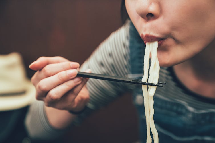 Japanese woman eats ramen from chopsticks.