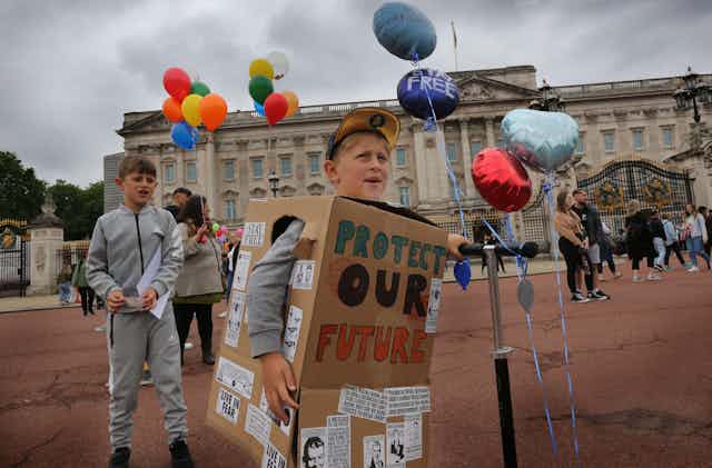 Two young boys take part in a protest with balloons and handdrawn signs