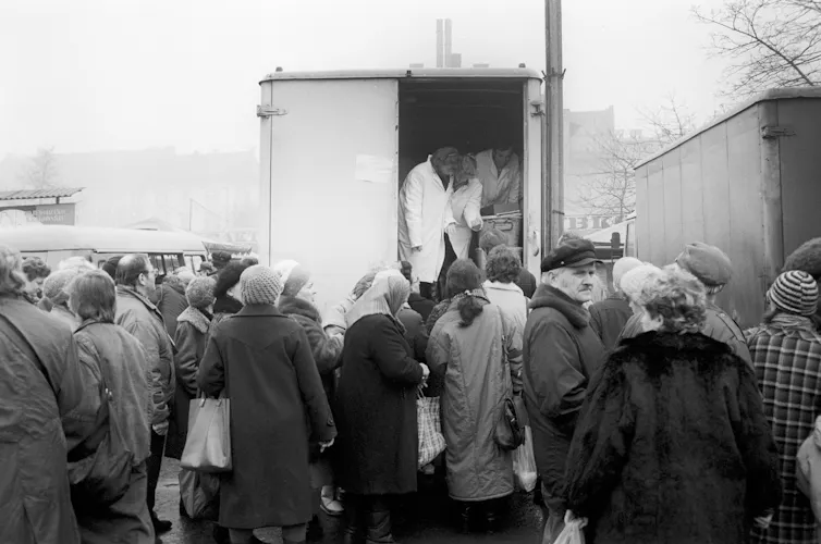 Black and white photo of people queuing for food.