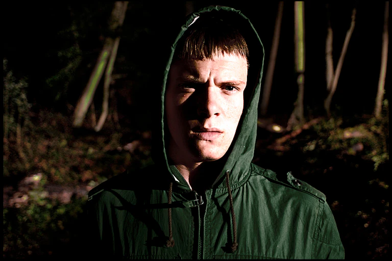 Boy in a rain coat with hood up.