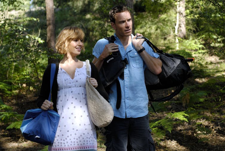 A young couple walk in the woods.