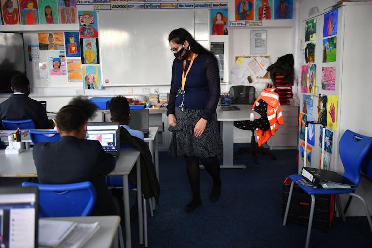 A teacher stands in a secondary school classroom with her pupils at their desks