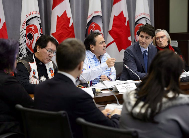 Justin Trudeau listens to Perry Bellegarde as he gestures during a meeting.