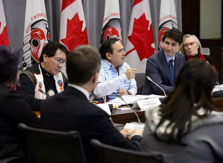 Justin Trudeau listens to Perry Bellegarde as he gestures during a meeting.