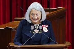 Mary Simon smiles as she speaks into a microphone.