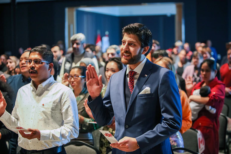 People raise their hands to take the oath of citizen ship.
