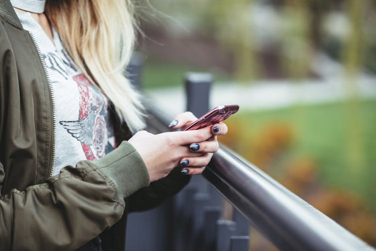 A woman's manicured hands on a cellphone.