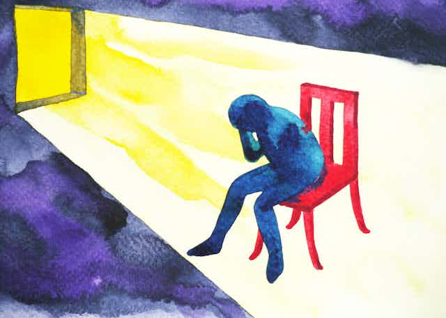 Illustration of blue human figure with its head in its hands, sitting in a red chair