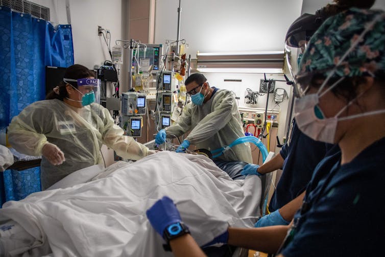 Health care workers attend to an unvaccinated COVID-19 patient at a medical center in Tarzana, California.