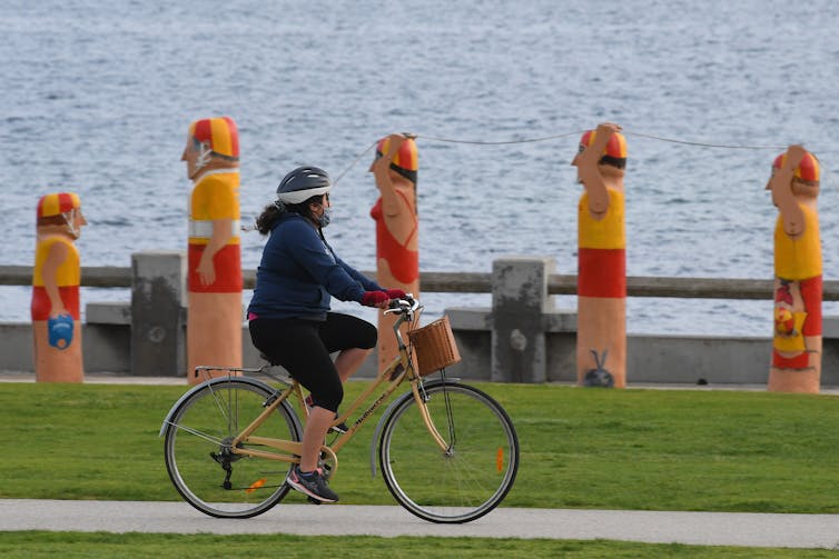 woman rides bike near water