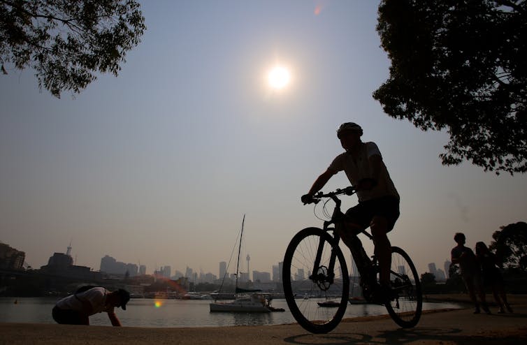 Silhouette of cyclists against sun and water