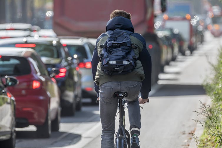 cyclist rides past row of cars