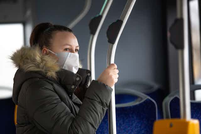 Masked woman on a bus looks out the window.
