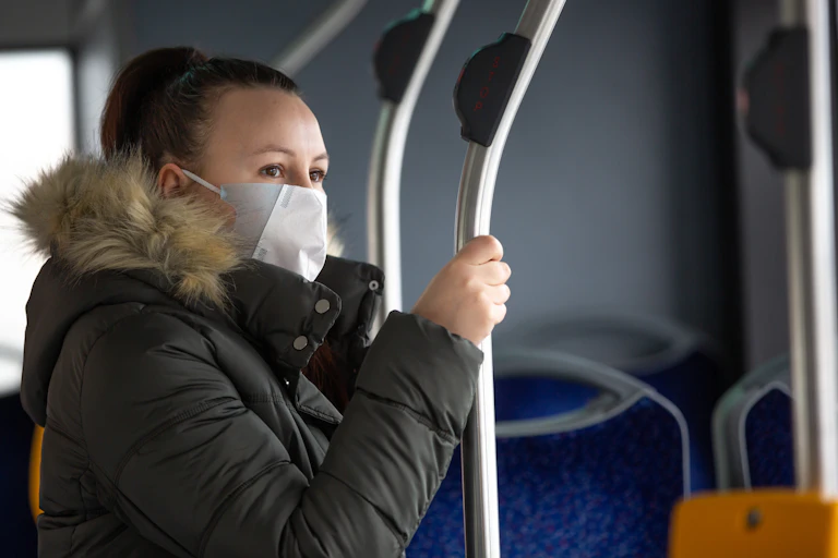 Masked woman on a bus looks out the window.